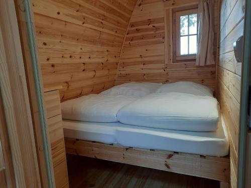 a bed in a wooden cabin with a window at 45 Camping Pod in Silberstedt