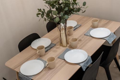 a wooden table with white plates and a vase with flowers at family apartment in Jerusalem