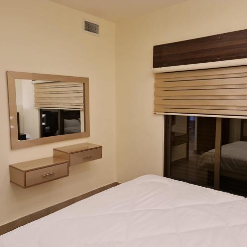 a bedroom with a bed with a mirror and a window at 24th Apartment in Amman