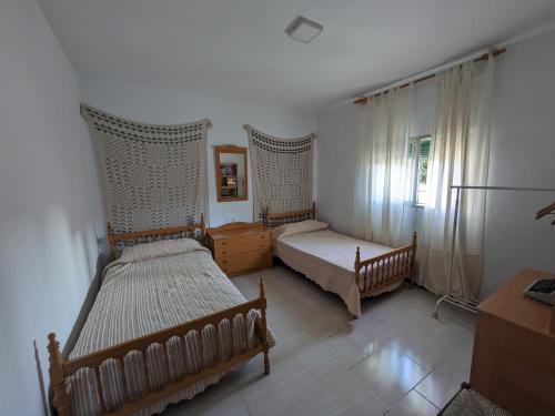 a bedroom with two beds and a desk and a window at Casa Virgen de Gracia in Archidona