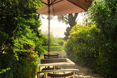 - une table de pique-nique et des chaises avec un parasol dans l'établissement Chambre indépendante au calme., à Herbignac