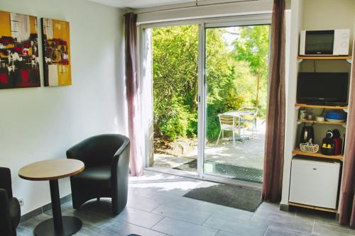 d'un salon avec une table et une porte coulissante en verre. dans l'établissement Chambre indépendante au calme., à Herbignac