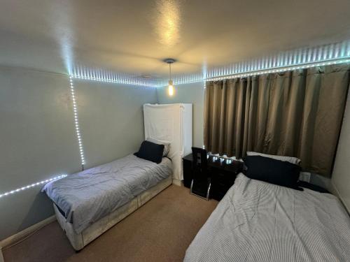 a bedroom with two beds and a window with lights at London gateway get-away in Hounslow
