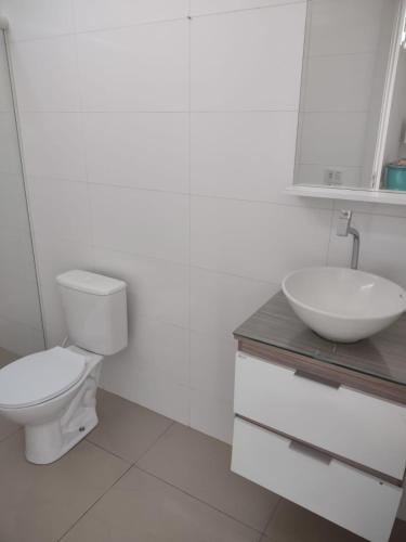 La salle de bains blanche est pourvue de toilettes et d'un lavabo. dans l'établissement St. Benoit suites e hostel, à Presidente Prudente