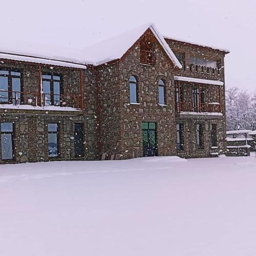 un gran edificio de ladrillo con nieve delante en Vachnadziani wine resort, en Gurjaani