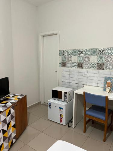 a kitchen with a table and a microwave on a counter at St. Benoit suites e hostel in Presidente Prudente