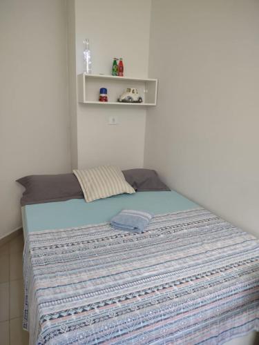 a bedroom with a bed with a blue blanket at St. Benoit suites e hostel in Presidente Prudente