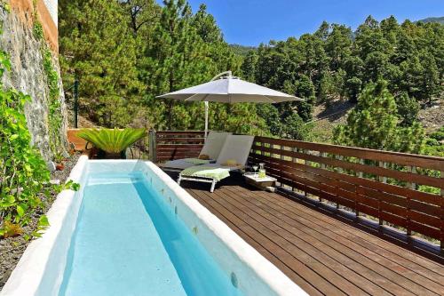 a swimming pool with an umbrella on a wooden deck at Ferienhaus mit Privatpool für 6 Personen ca 150 qm in El Paso, La Palma Westküste von La Palma in El Paso