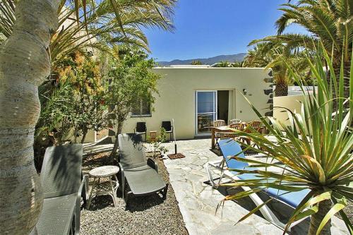 una casa y un patio con sillas y mesas. en Ferienhaus für 4 Personen ca 75 qm in Puerto Naos, La Palma Westküste von La Palma en Puerto Naos