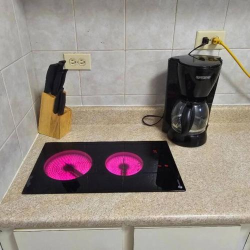 a kitchen counter with a stove top with pink lights at Golden Dream Villas & Studio A/B Pool View in Isabela