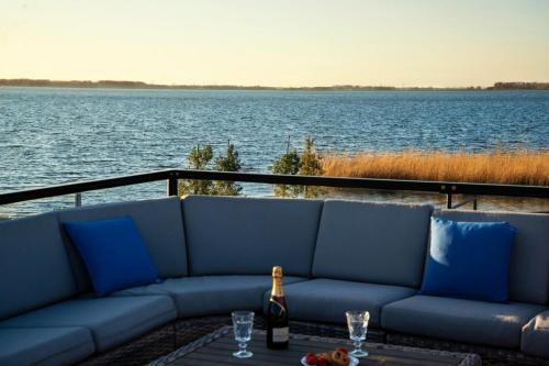 uma garrafa de vinho sentada num sofá ao lado da água em Royale Cube mit Dachterrasse Meerblick und Strand em Hulshorst