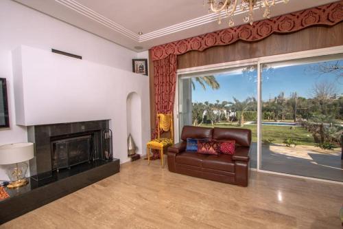 a living room with a leather couch and a fireplace at Villa Meriem, Fès in Oulad Tayeb