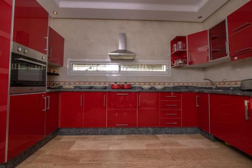 a red kitchen with red cabinets and a window at Villa Meriem, Fès in Oulad Tayeb