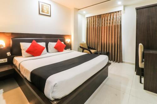 a hotel room with a large bed with red pillows at Capital O Hotel Krishna in Jaipur
