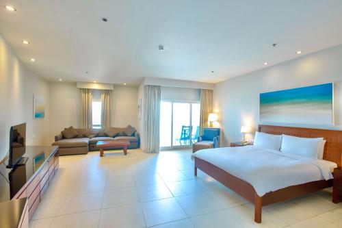 a bedroom with a bed and a living room at Radisson Blu Resort, Fujairah in Dibba