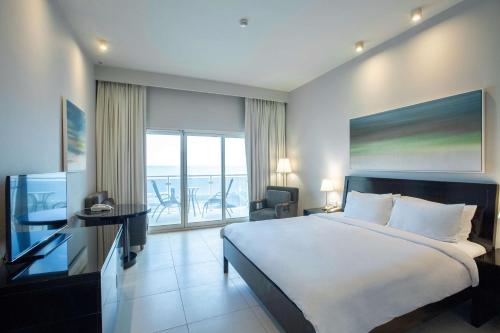 a bedroom with a large bed and a balcony at Radisson Blu Resort, Fujairah in Dibba