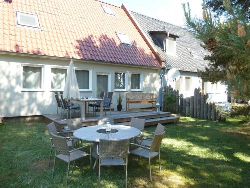 a patio with tables and chairs in a yard at Ferienhaus Boddenblick mit Sauna in Pruchten