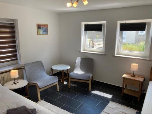 a room with two chairs and two tables and two windows at Ferienapartment Dörfles-Esbach in Dörfles