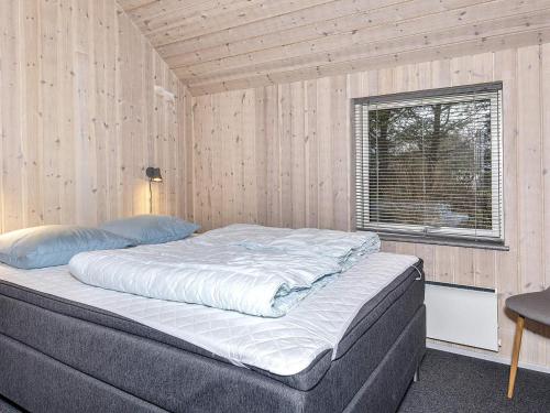 Holiday home Farsø VIII في Farsø: سرير في غرفة بجدار خشبي