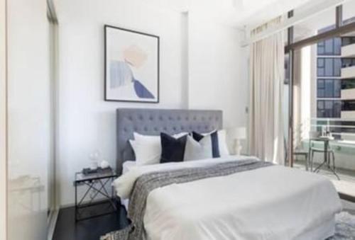 a white bedroom with a large bed and a window at One Bedroom Unit at Sydney Best Location in Sydney