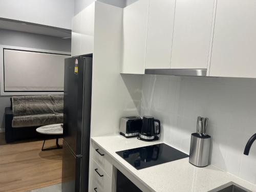 une cuisine avec des armoires blanches et un réfrigérateur noir dans l'établissement Northcott Lodge, à Adamstown