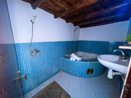 W łazience znajduje się wyłożona niebieskimi kafelkami wanna i umywalka. w obiekcie Auberge le Refuge w mieście Agadir