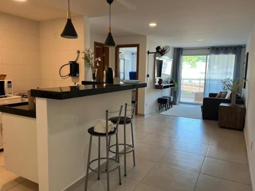 uma cozinha e sala de estar com um balcão e bancos em Apartamento Por do sol Le Bon Vivant em Arraial do Cabo