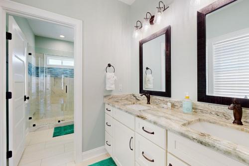 Un baño blanco con dos lavabos y una ducha. en Seabirds, en Sunset Beach