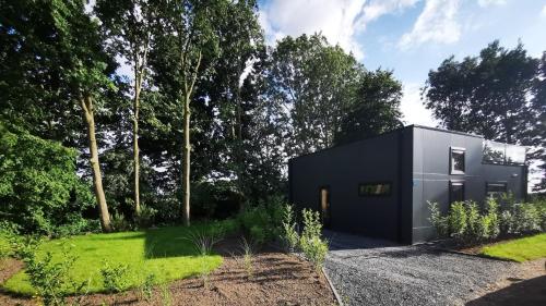 Strand & Veluwemeer - Cube Elite Premium Bad Hoophuizen في هولْسْهورست: منزل أسود في حديقة بها أشجار