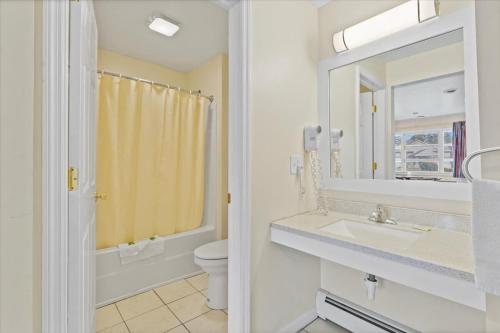ein Badezimmer mit einem Waschbecken, einem WC und einem Spiegel in der Unterkunft Top Hill Motel in Saratoga Springs