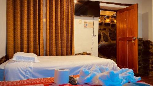 a bedroom with a white bed and a table with shoes at Inca viewpoint in Ollantaytambo