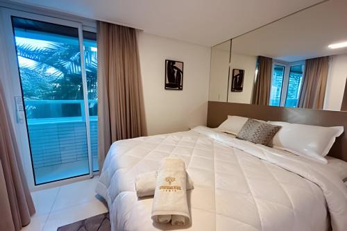 um quarto com uma grande cama branca e uma grande janela em Apto Luxo 2 quartos no Solar Tambaú em João Pessoa