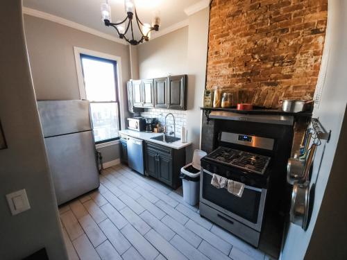 a kitchen with an oven and a brick wall at Historic Bushwick, Brooklyn Brownstone Apartment in Brooklyn
