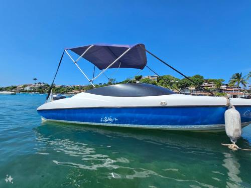 a blue and white boat sitting in the water at CALUIII in Búzios