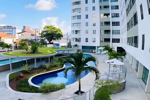 an apartment complex with a pool and a palm tree at Aptos no Luxor Tambaú próximo ao mar in João Pessoa