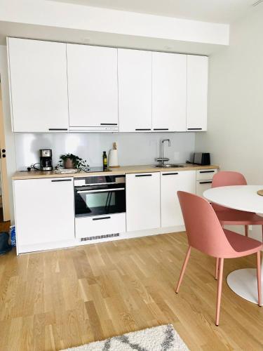 uma cozinha com armários brancos e uma mesa em 2 Bedroom Rose Charm - by University em Kokkola