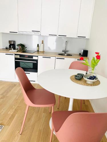 a white kitchen with a white table and pink chairs at 2 Bedroom Rose Charm - by University in Kokkola