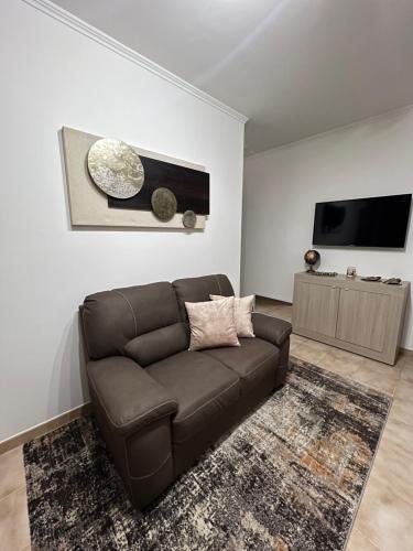 een woonkamer met een bruine bank en een flatscreen-tv bij a casa di Lalla in Borgo Podgora