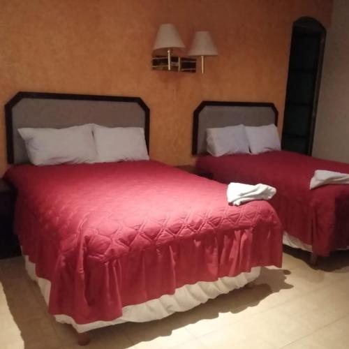 2 letti con coperte rosse in una camera di Hotel Real Doxey a Tlaxcoapan