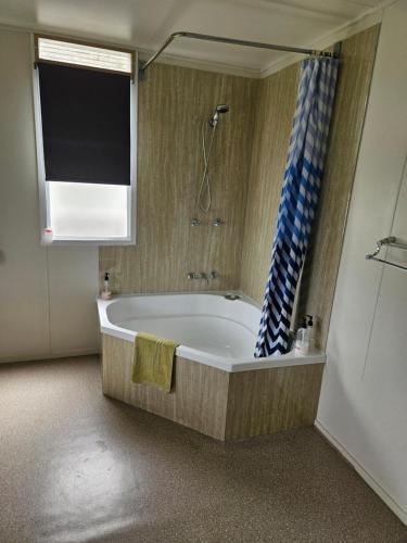 baño con bañera con ducha y ventana en CHURCHILL COTTAGE- 94 Churchill St Maryborough QLD, en Maryborough