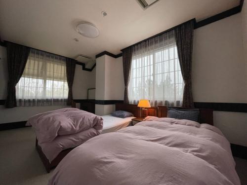 Koguriyama Sanso - Vacation STAY 37442v في Minami Uonuma: سريرين في غرفة بها نافذتين