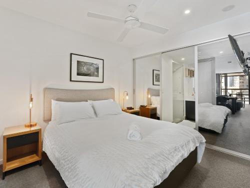 1 dormitorio con 1 cama blanca grande y espejo en Discover urban bliss in our 1-bedroom King bed apartment! City views and cultural gems en Brisbane