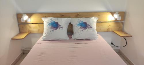 una camera da letto con un letto con due cuscini di Bungalow Touloulou (Mi) à 10mn à pieds des plages a Le Gosier