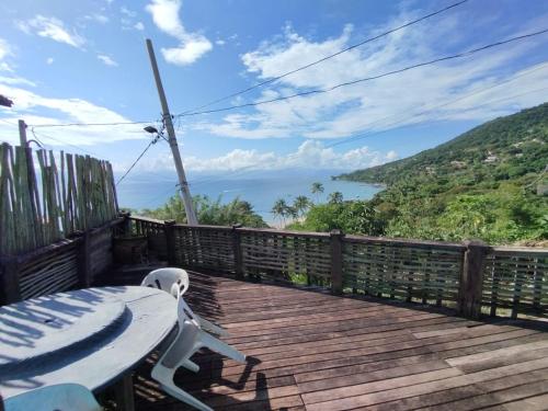 a wooden deck with a table and a view of the ocean at Refúgio na Praia in Ilhabela