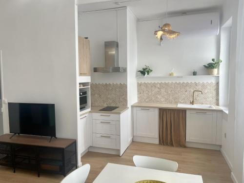 Il comprend une cuisine avec des placards blancs, une table et une télévision. dans l'établissement Confort & Calme - Proche de la mer, métro, centre ville et stade, à Marseille