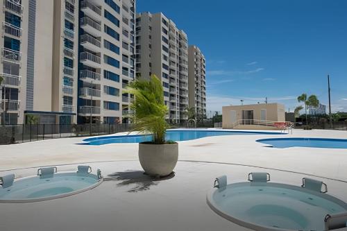 a swimming pool with a potted plant and buildings at Apto completo Pto Azul Club House Ven a Descansar in Ricaurte