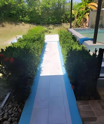 a garden with a blue walkway next to a pool at Hermosa finca plan ecológico Brisas de 4 Esquinas in Carmen de Apicalá
