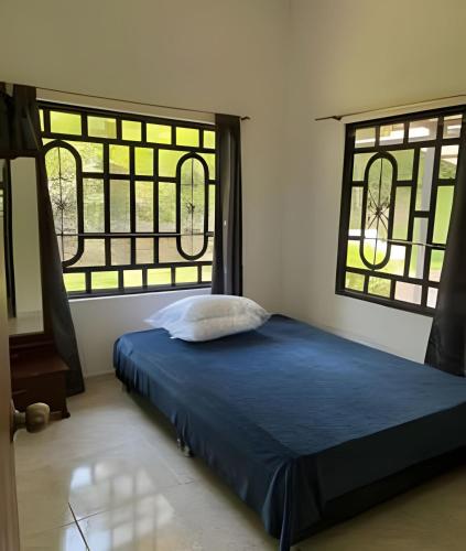 a bed in a room with two windows at Hermosa finca plan ecológico Brisas de 4 Esquinas in Carmen de Apicalá