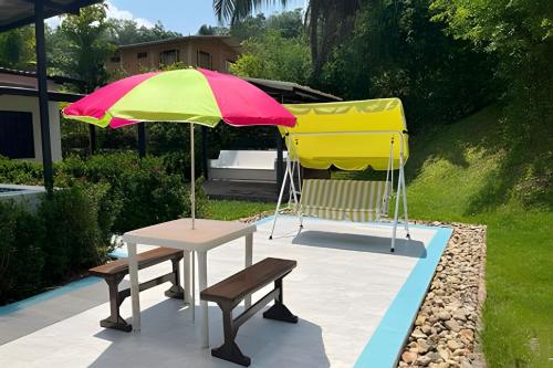 a table and a chair under a colorful umbrella at Hermosa finca plan ecológico Brisas de 4 Esquinas in Carmen de Apicalá