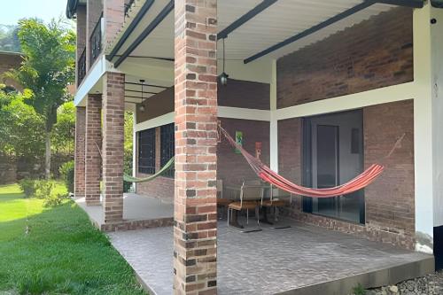a house with a patio with a table and red rope at Hermosa finca plan ecológico Brisas de 4 Esquinas in Carmen de Apicalá